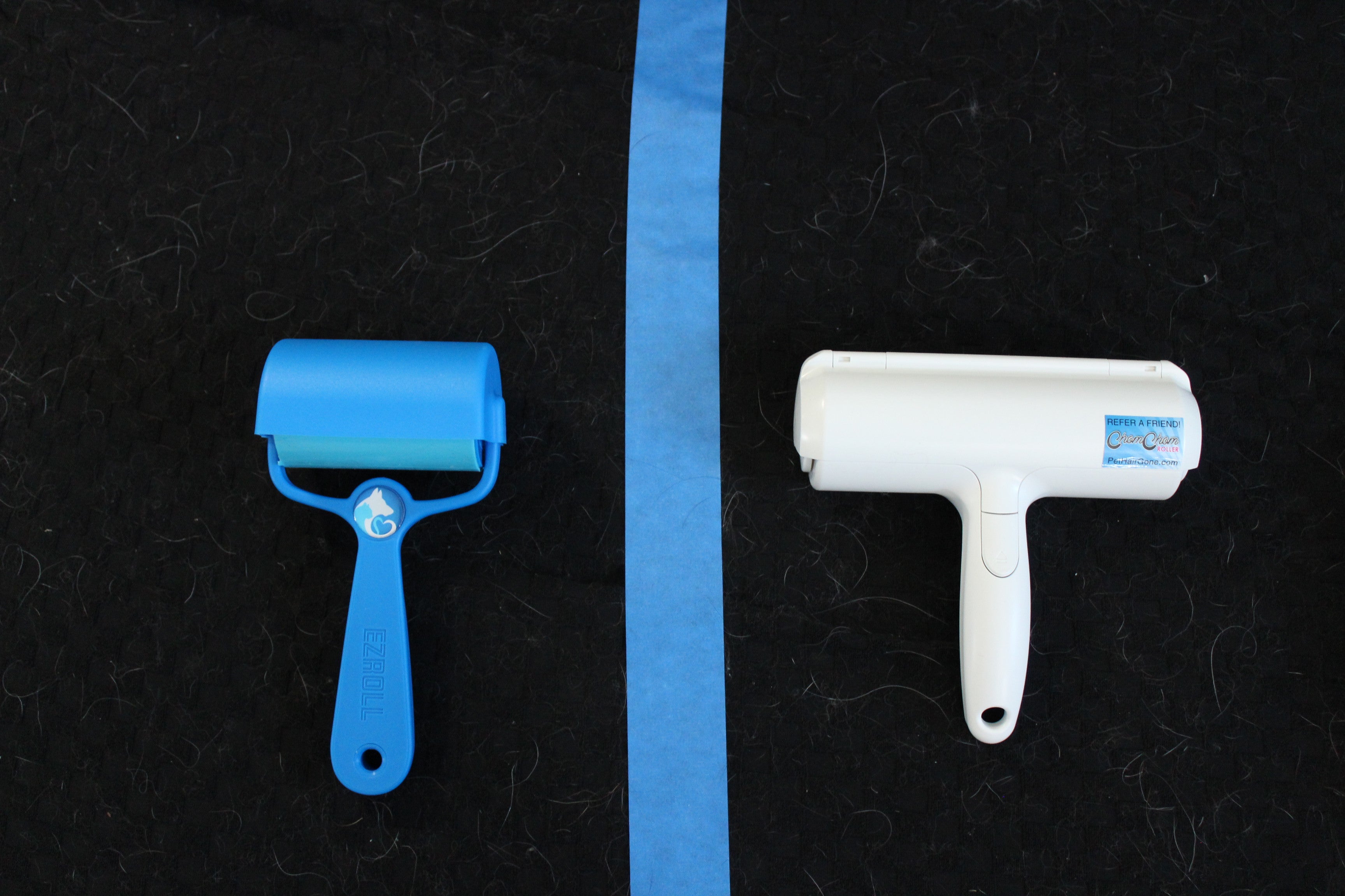 PetLovers EzRoll blue silicone reusable lint roller on the left next to a ChomChom roller on the right, photographed on a black fabric surface divided by blue painter's tape
